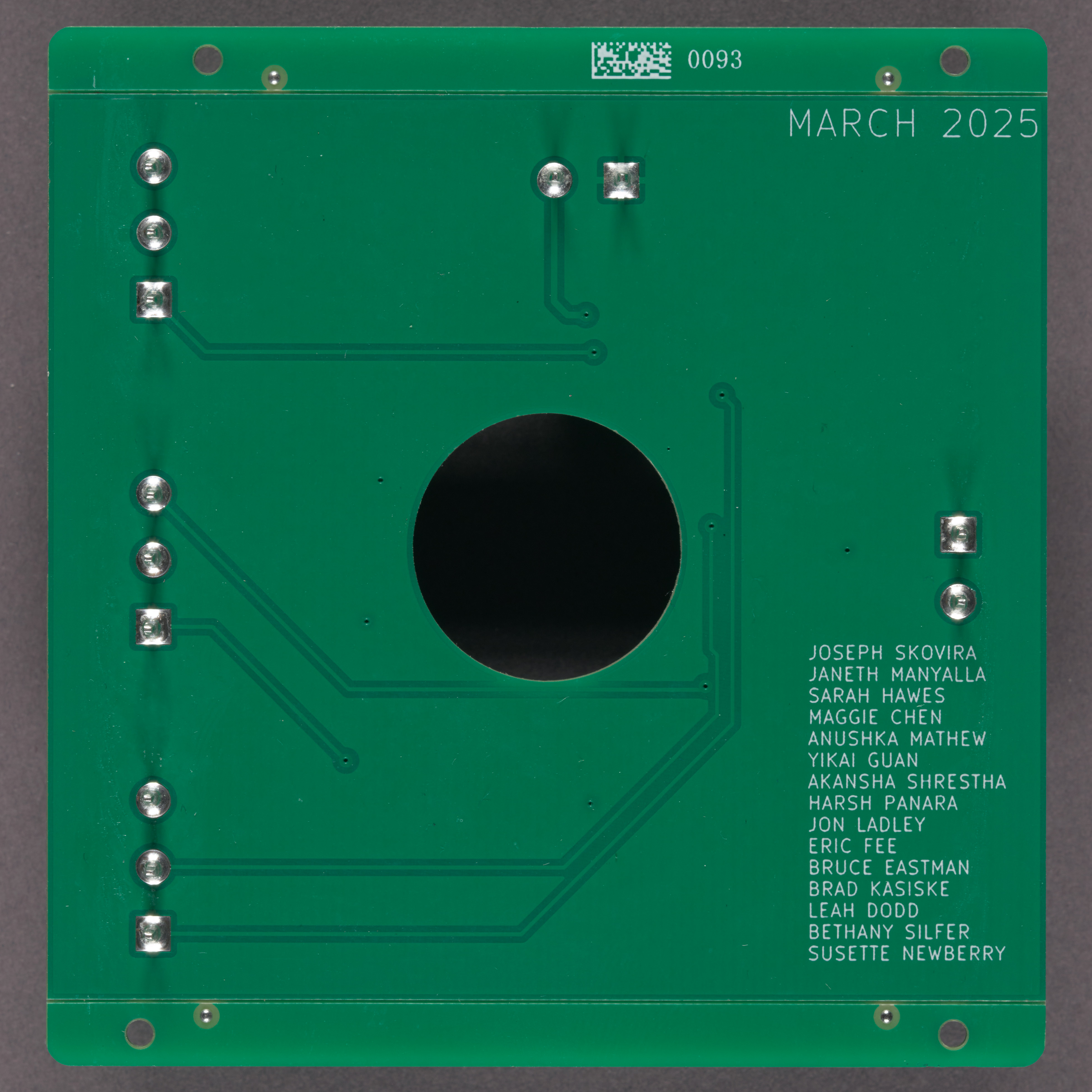 The back of a green LED circuit board. Several names are listed in the bottom right corner. 